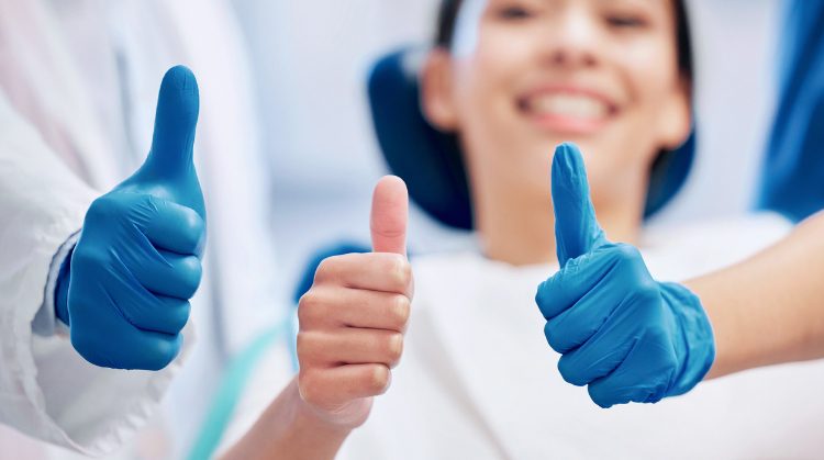 Smiling patient giving a thumbs up with gloved hands beside them.