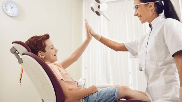 Young boy giving high-five to dentist after dental checkup.
