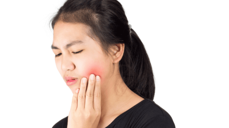 Person holding their cheek in pain from a toothache at Dental Nation in Las Vegas, NV.
